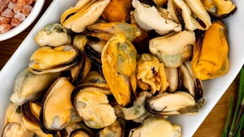 Cooked mussels in shell on white plate with pink himalayan salt Stock Footage 347792586