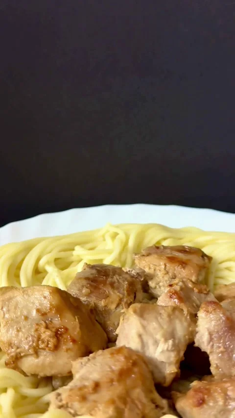 Cooked noodles with fried meat chunks on a plate Video stock 334593109