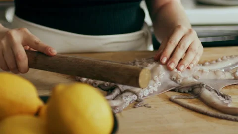 Cooked octopus being tenderized on a cutting board in a large well appointed kit Stock Footage 199459720
