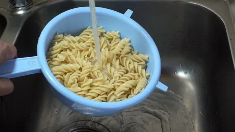 Cooked pasta in a colander is washed in slow motion under running water Stock Footage 126893119