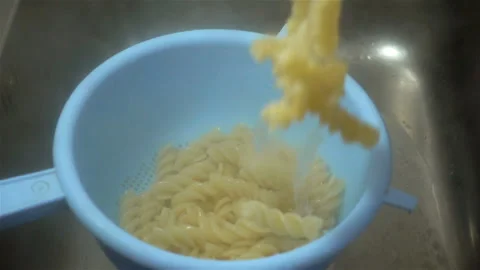 Cooked pasta is poured into a colander in slow motion Stock Footage 158909703