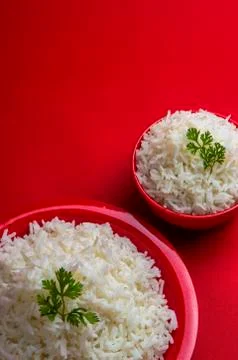 Cooked plain white basmati rice in bowl and plate on red background. Stock Photos