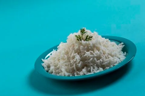 Cooked plain white basmati rice with corriander in a blue plate on blue backg Stock Photos
