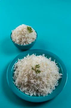 Cooked plain white basmati rice in a blue plate and bowl on blue background Stock Photos