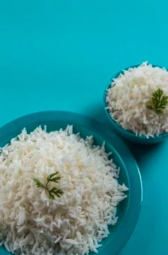 Cooked plain white basmati rice in a blue plate and bowl on blue background Stock Photos
