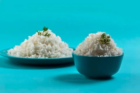 Cooked plain white basmati rice in a blue plate and bowl on blue background Stock Photos