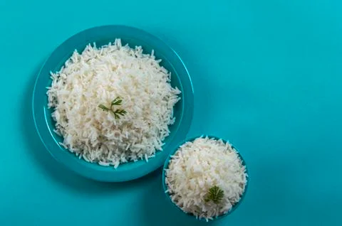 Cooked plain white basmati rice in a blue plate and bowl on blue background Stock Photos