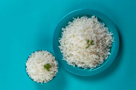 Cooked plain white basmati rice in a blue plate and bowl on blue background Stock Photos