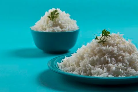 Cooked plain white basmati rice in a blue plate and bowl on blue background Stock Photos