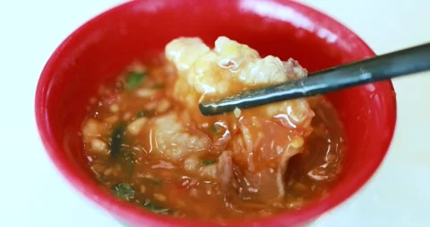 Cooked pork or meat held with chopsticks over a bowl of spicy red soup, Asi.. Stock Footage 346686862