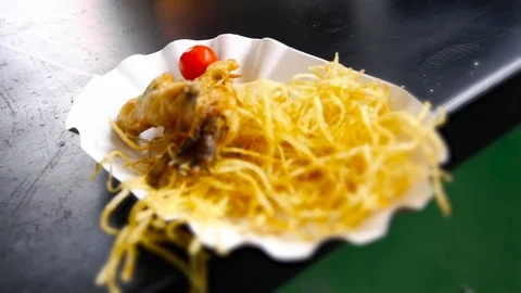 Cooked Potato straws and frog legs in batter on a disposable plate Stock-Footage 84252322