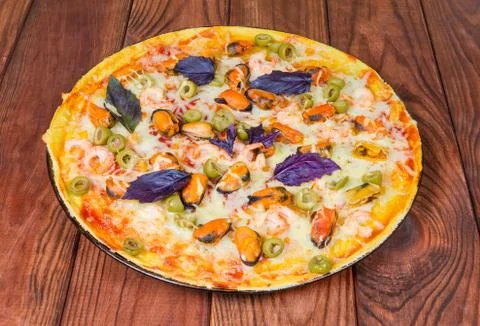 Cooked round pizza with seafoods on rustic wooden table Stock Photos