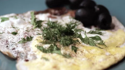 Cooked scrambled eggs with bacon slices, herbs, olives are in a large platter. Stock Footage 146335428