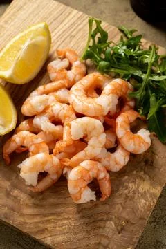 Cooked shrimps with lemon and rucola on wooden board. Stockfoto's