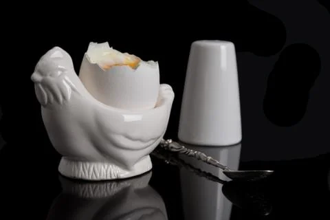 Cooked soft boiled egg, salt shaker and spoon Stock Photos