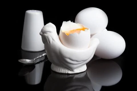 Cooked soft boiled egg, salt shaker and spoon Foto stock