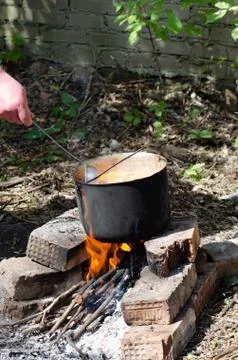 Cooked soup in a cauldron on open fire Stock Photos