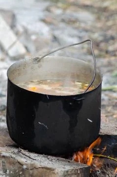 Cooked soup in a cauldron on open fire Stock Photos