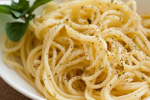 Cooked Spaghetti in a big white spoon with oregano. Stock Photos
