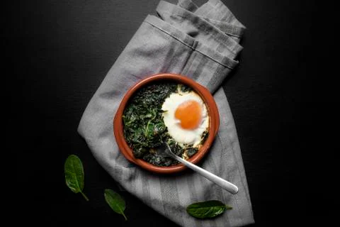Cooked spinach and baked egg in a clay pot Stock Photos