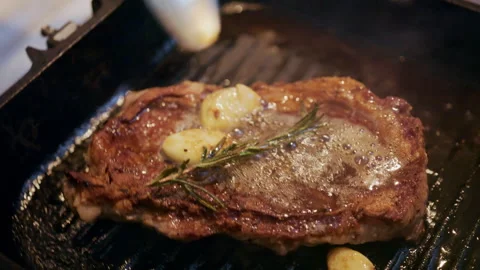 Cooked steak browning in a grill pan while being basted with melted butter and Video stock 329401248