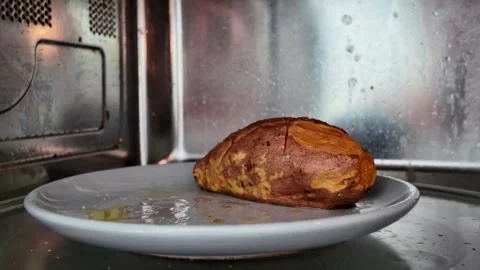 Cooked Sweet Potato Rotating Inside Microwave Oven On Glass Turntable Plate Stock Footage 339031992