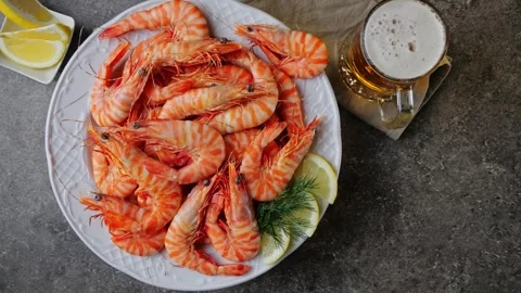 Cooked tiger shrimp on a plate rotating. Glass of beer. Top view Stock Footage 260473940