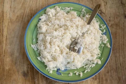 Cooked white basmati rice served on green plate with spoon Stock Photos