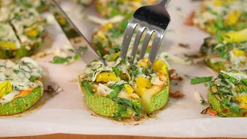 Cooked zucchini stuffed with cheese is cut in half using a knife and fork Stock Footage 270146203