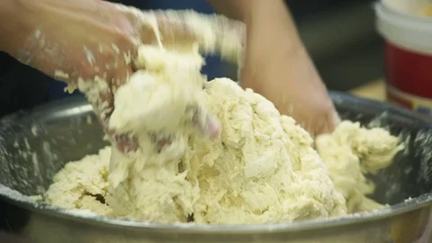 Cooker kneads dough with both hands in bowl in industrial kitchen Stock Footage 71521689