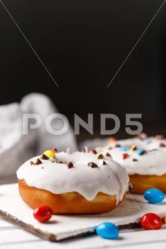Cookery, baking and food concept - closeup. Donuts in white glaze with colore Stock Photos