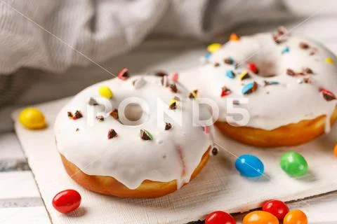 Cookery, baking and food concept - closeup. Donuts in white glaze. Stock Photos