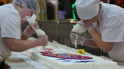 Cookery hands of culinary experts squeeze the cream on a big white cake Stock Footage 61682097