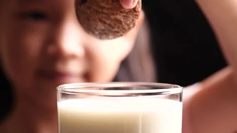 Cookie and Milk, Biscuit. Child girl dipping chocolate chip cookie in milk Stock Footage 226503644