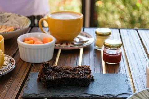 Cookie cake on a slate board, next to assorted jams, papaya and cup of latte. Stock Photos