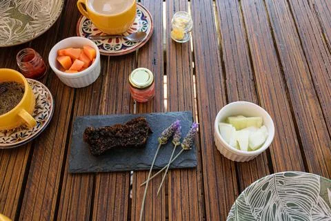 Cookie cake on a slate stone, next to lavender flowers, melon and a small emp Stock Photos