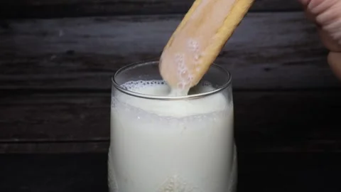 A cookie is dipped into a glass of milk Stock Footage 345416837