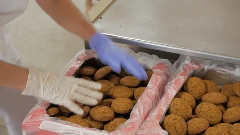Cookie factory workers are sorting and packing oat biscuits on stainless steel Stock-Footage 110876115