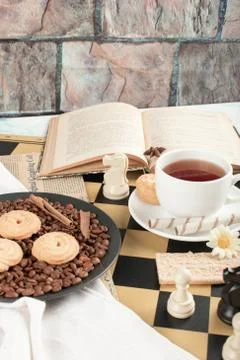 Cookie platter and a cup of tea on the chessboard Stock Photos