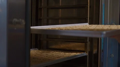 A cookie sheet is placed in a professional cooking oven. Woman cook Stock Footage 125956967