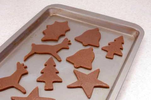 Cookie sheet with uncooked festive gingerbread biscuits Stock Photos