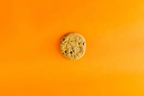 A cookie is sitting on a bright orange background Stock Photos