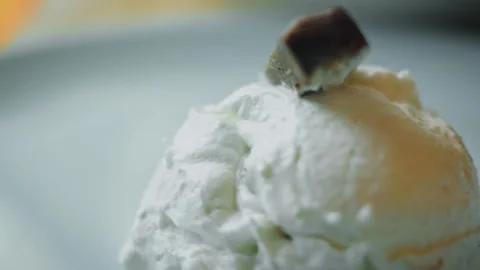 Cookie-topped vanilla ice cream melting in warm side light, 4K Stock Footage 341119414