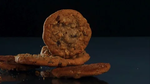 Cookies fall onto dark reflective surface slowly Stock Footage 326755721