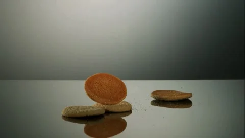 Cookies falling and bouncing on a dark reflective surface Stock Footage 327514285