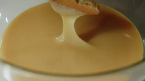 Cookies in milk. A thin stream of condensed milk flows into the bowl. Close up Stock Footage 241564332