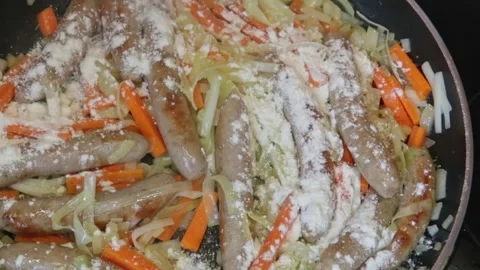 Cooking: Adding flour to a sausage casserole Video stock 278348332