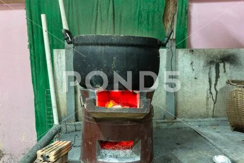 Cooking aluminum pot boiling on charcoal burning stove. Stock Photos