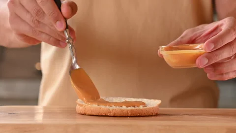 Cooking and assembling hot tasty burger. Spooning cheese sauce into a burger Stock Footage 296071760