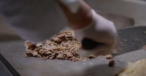 Cooking and chopping an authentic Philly Cheesesteak on a restaurant griddle Stock Footage 85041716